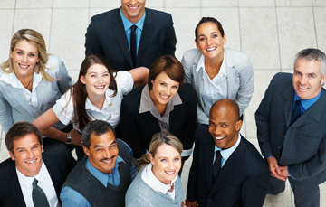 A diverse group of business professionals smiling and looking up.
