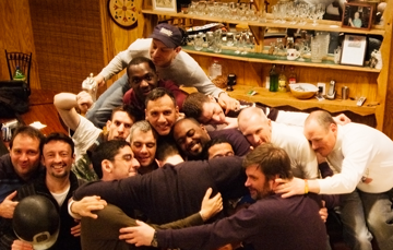 A group hug among friends in a cozy bar setting.
